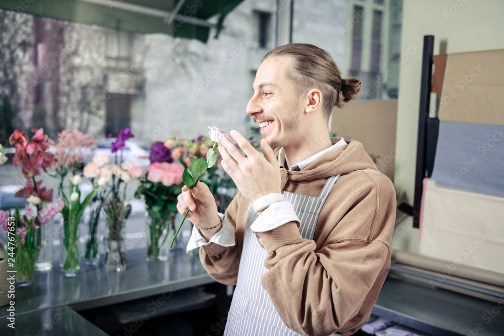 Handsome gardener smelling rose with sincere smile Handsome gardener smelling rose with sincere smile