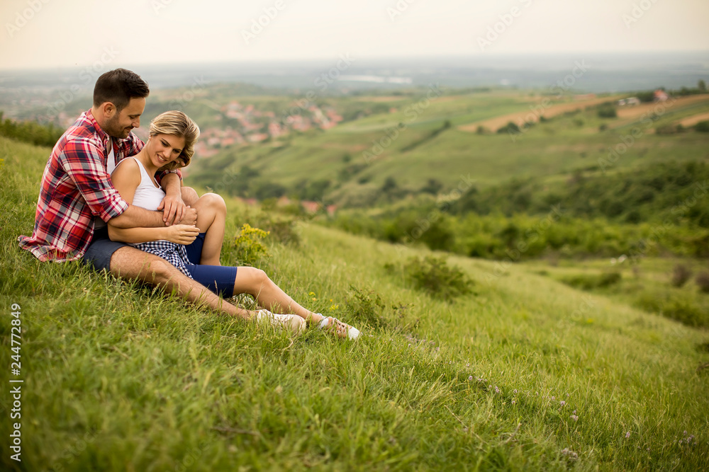 Loving couple sitting  hugged on grass in the mountain