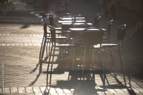Canvas Print empty set of tables and chairs outside a cafe glistening in the early morning su