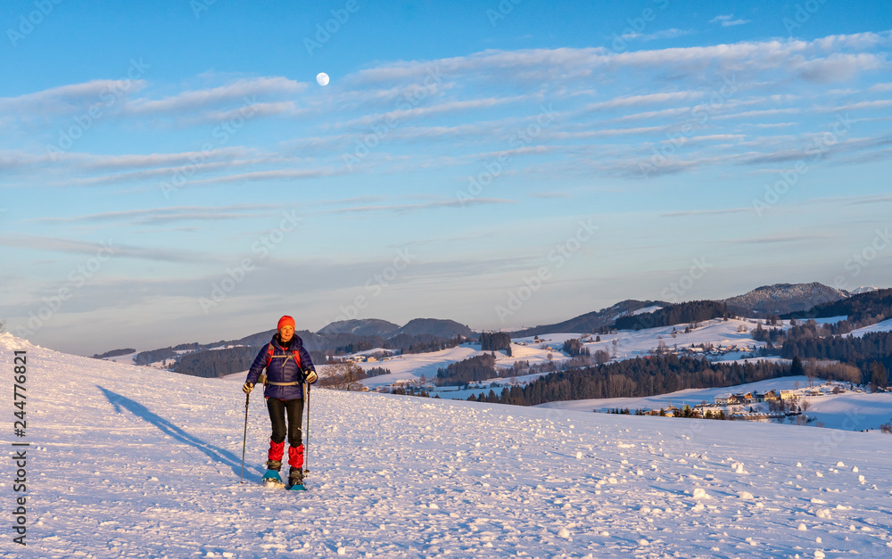 active senior woman snowshoeing in the Allgaeu Alps near Oberstaufen, Bavaria, Germany