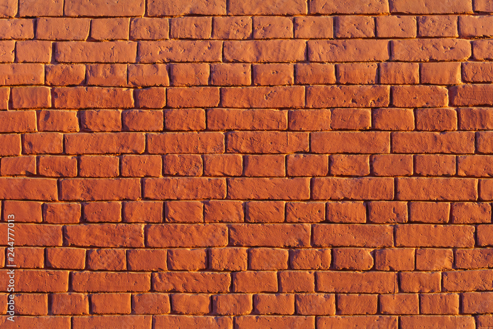 Fototapeta premium Red brick wall illuminated by the sun, texture