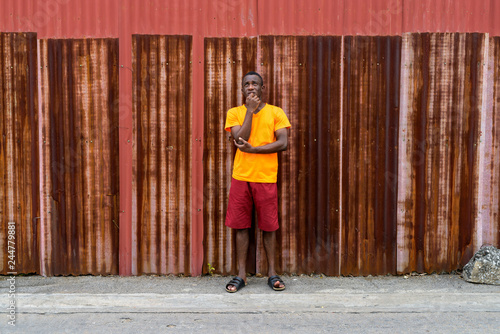 Young black African man standing while thinking against old rust
