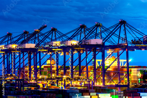 Container Cargo freight ship with working crane bridge in shipyard at dusk