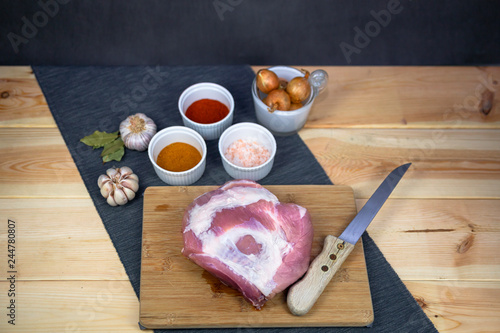 Pork ham on wooden board with onion, garlic and spices