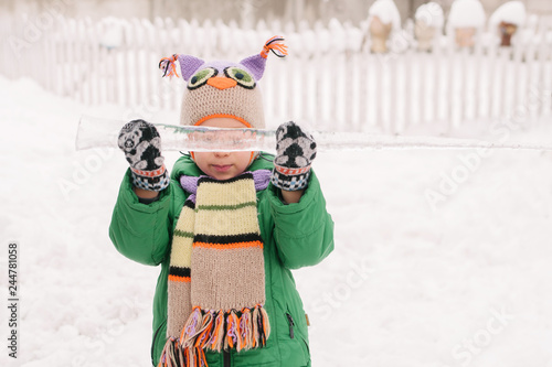 winter portrait of a little boy with an icicle