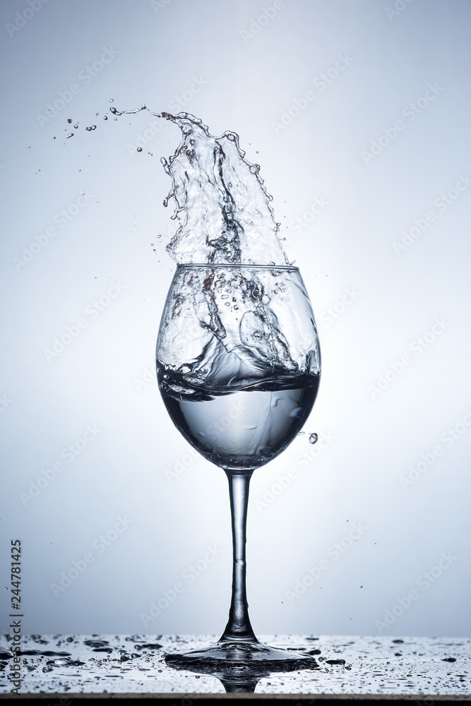 Splashing water on blue background. Wine glass with water. Splashing water on blue background. Wine glass with water.