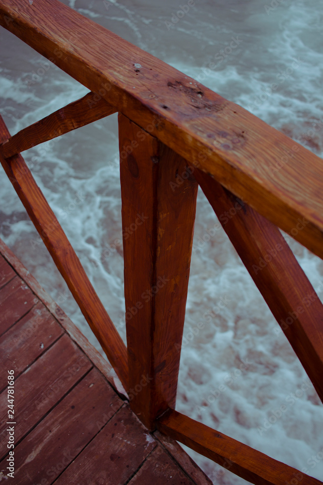  fragment of a wooden bridge against the sea during a storm
