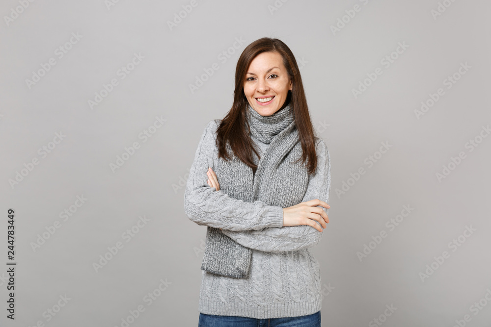 Young woman in gray sweater, scarf holding hands folded isolated on grey wall background, studio portrait. Healthy fashion lifestyle, people sincere emotions, cold season concept. Mock up copy space. Young woman in gray sweater, scarf holding hands folded isolated on grey wall background, studio portrait. Healthy fashion lifestyle, people sincere emotions, cold season concept. Mock up copy space.
