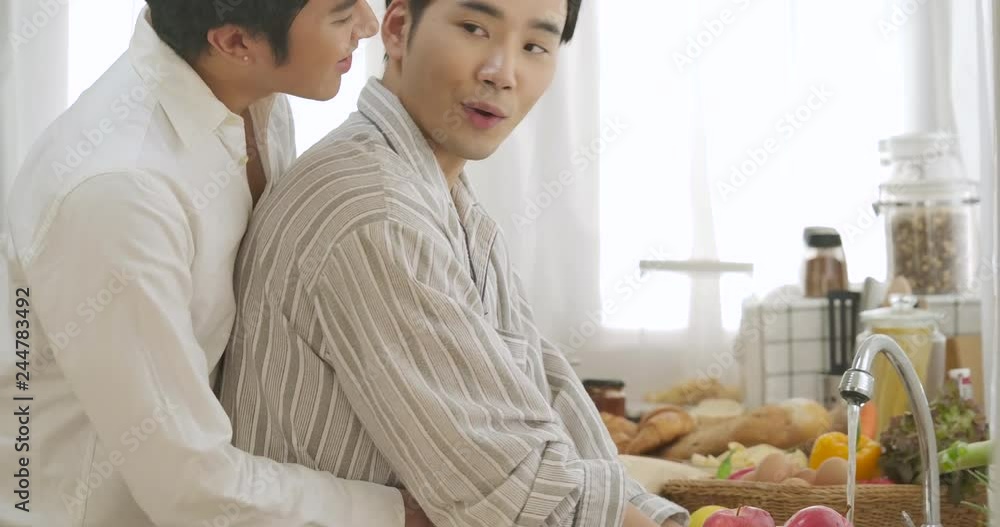 Happy gay couple cooking together in home kitchen. People with gay, homosexual, relationship concept.