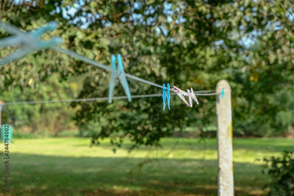Wäscheleine mit blauen Wäscheklammern im Garten, fokusiert Wäscheleine mit blauen Wäscheklammern im Garten, fokusiert