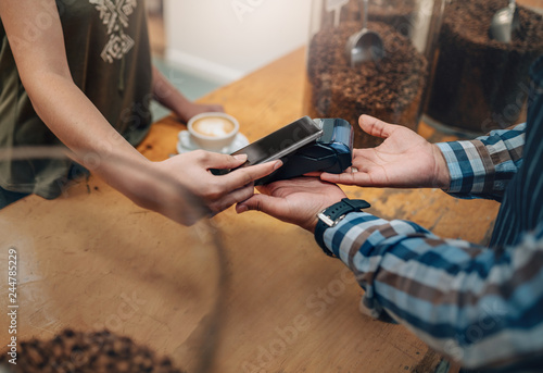 Customer making wireless or contactless payment using credit card using NFC technology. focus on hands © JonoErasmus