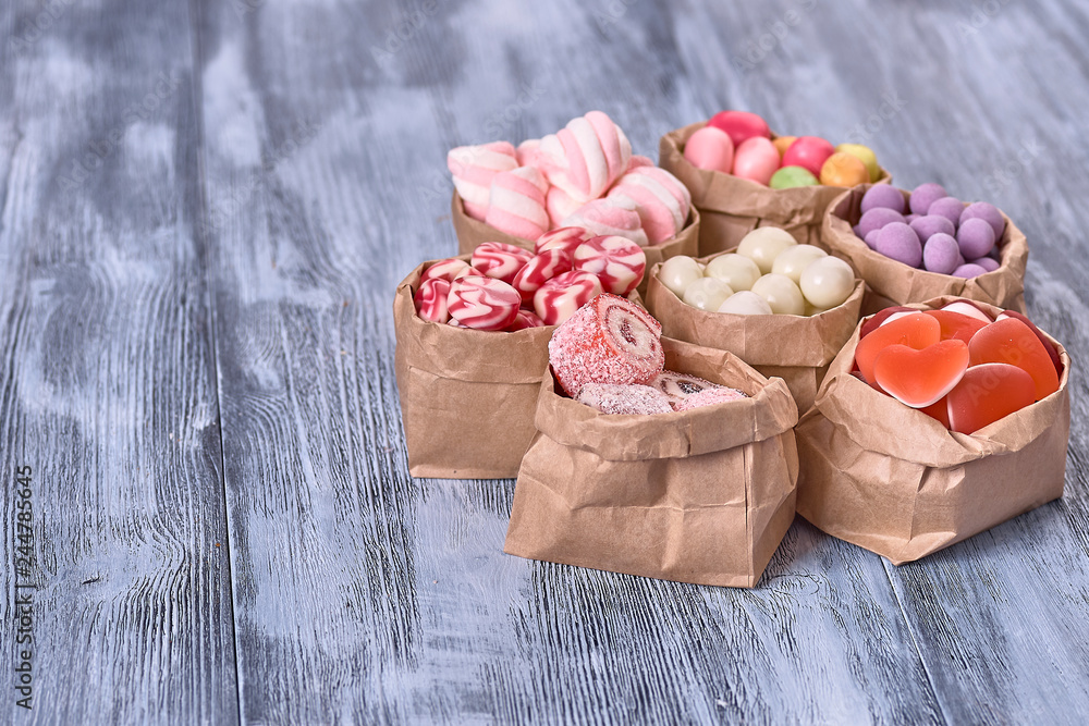 Colored candy in paper bags on wooden background Colored candy in paper bags on wooden background