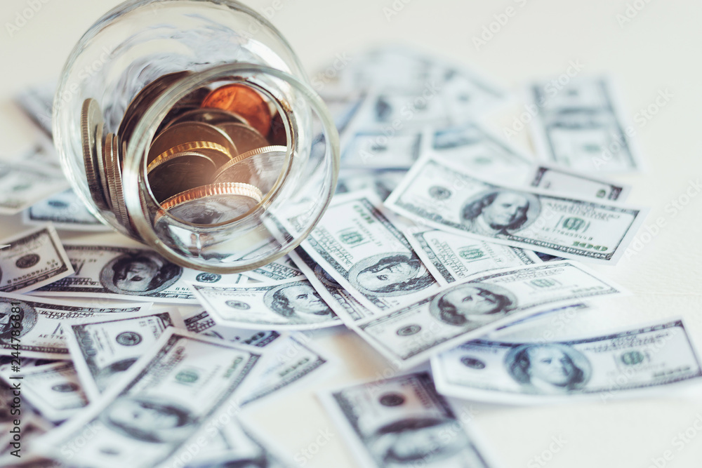 Close up coins in glass jar with dollar bill for money saving. selective focus Close up coins in glass jar with dollar bill for money saving. selective focus