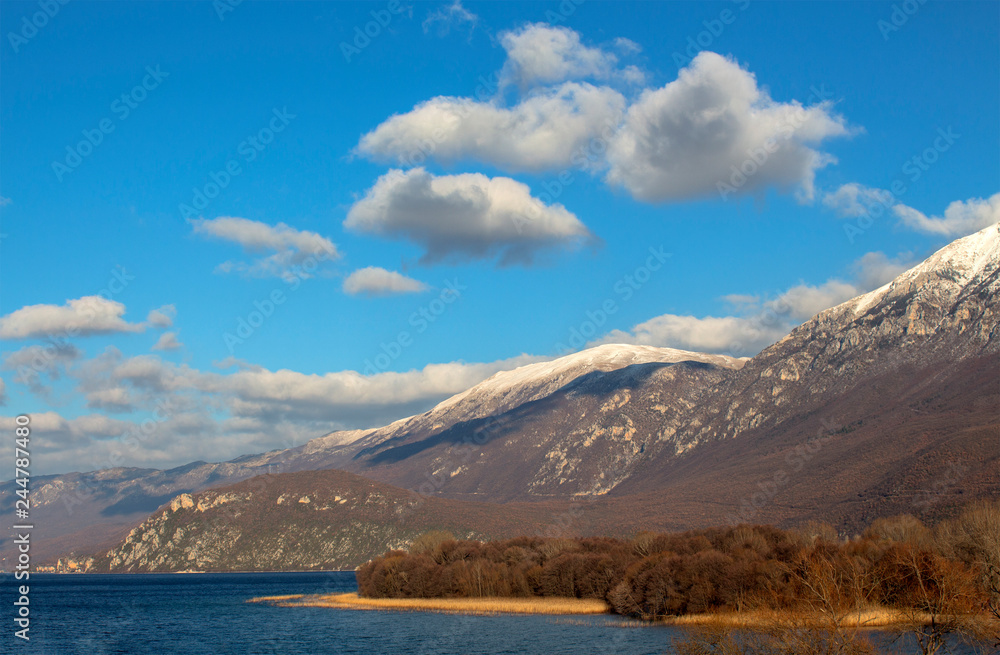 Winter landscape in Macedonia. Ohrid Lake and the picturesque hills of Galichitsa mountain under the blue sky with white clouds.
