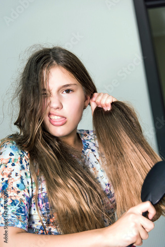girl with a comb looking into the camera, her hair problem. Funny teen girl