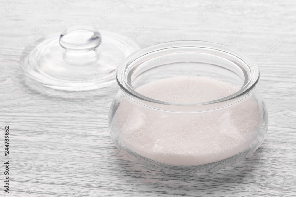 Glass transparent container with sugar on a white old wooden table Glass transparent container with sugar on a white old wooden table
