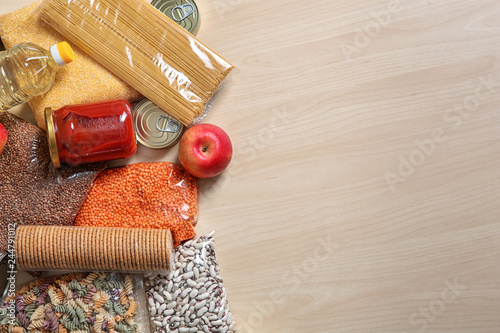 Many different products and space for text on wooden background, flat lay. Food donation