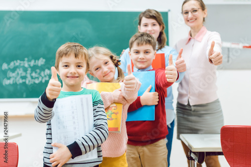 Pupils and teacher showing thumbs-up in school having fun in class