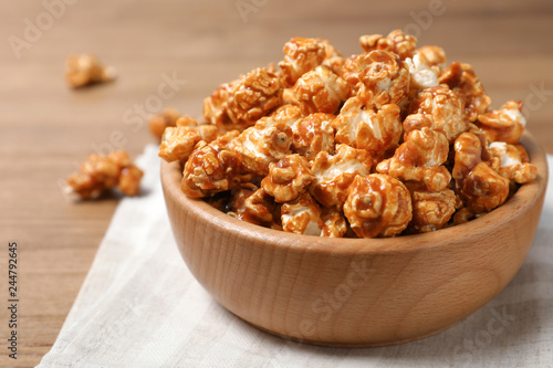 Wooden bowl with tasty caramel popcorn on table