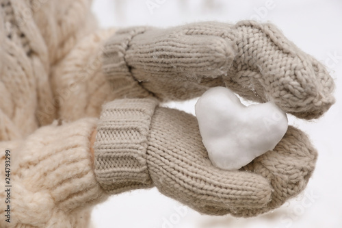 Woman holding heart made of snow, closeup view