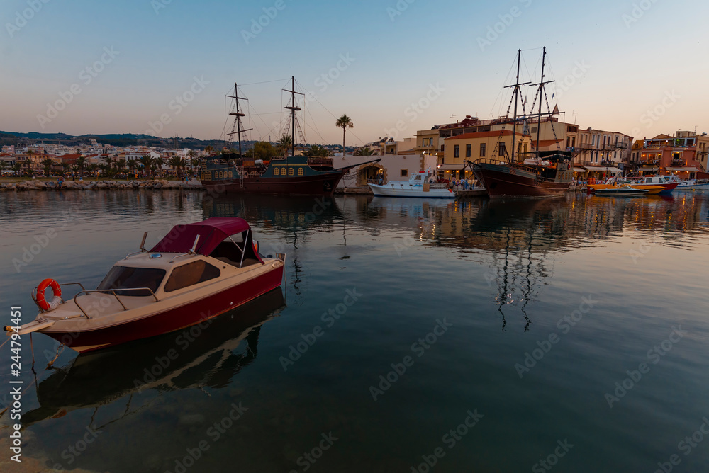 Fototapeta premium Greece, Crete Rethymnon. Old venetian harbor at the evening. Panoramic view on the port and sailing ship.