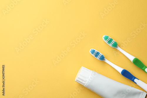 Blank tube of toothpaste and brushes on color background  top view with space for text