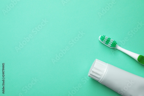 Blank tube of toothpaste and brush on color background  top view with space for text