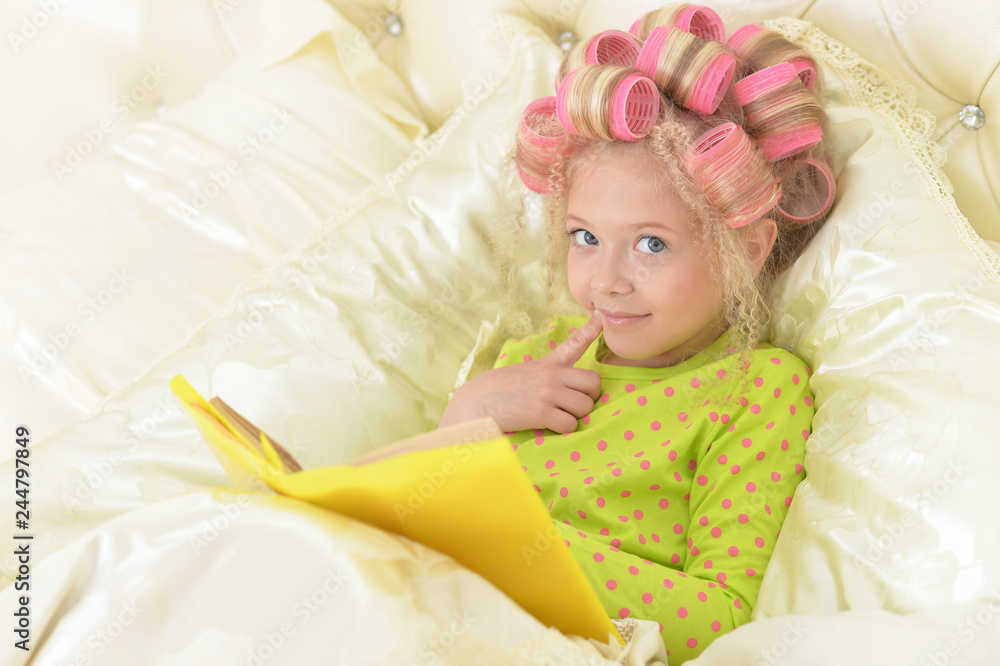Lovely little girl with pink curlers reading Lovely little girl with pink curlers reading