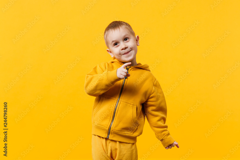 Little cute kid boy 3 4 years old wearing yellow clothes isolated on bright orange wall background children studio portrait. People sincere emotions childhood lifestyle concept. Mock up copy space. St...