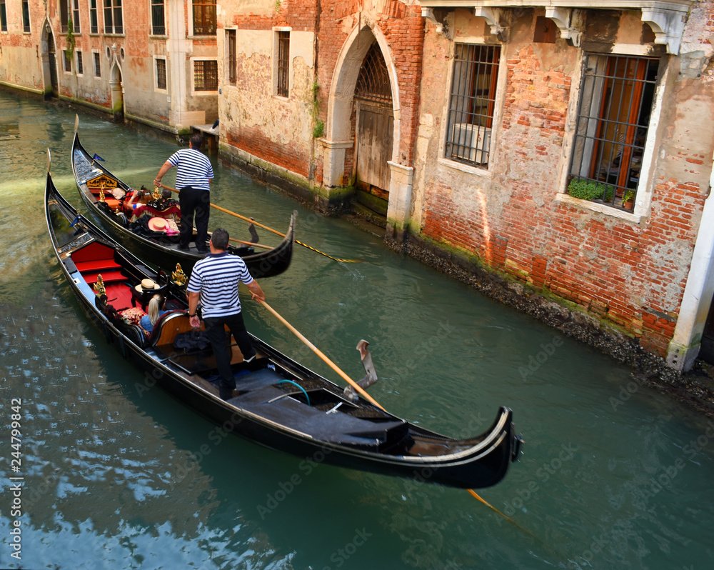 Two Gondolas navigating small Venice Canal.