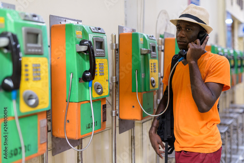 African tourist man talking on payphone and thinking