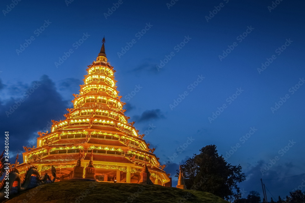 Fototapeta premium Wat Huay Pla Kang, beautiful golden pagoda chinest style decorate with lighting at night with cloudy sky background, chinese temple in Chiang Rai, Thailand.