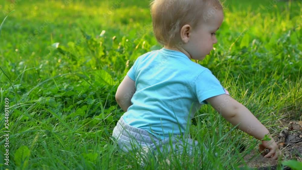 Baby boy touching green grass in the park, slow motion 120 fps Baby boy touching green grass in the park, slow motion 120 fps