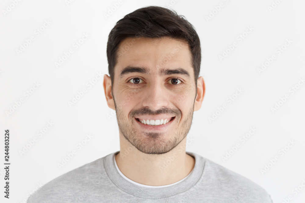 Close-up portrait of smiling handsome unshaven man isolated on gray background Close-up portrait of smiling handsome unshaven man isolated on gray background