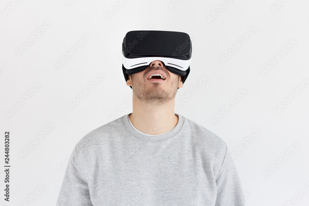 Amazed man experiencing virtual reality with VR headset, isolated on gray background Amazed man experiencing virtual reality with VR headset, isolated on gray background