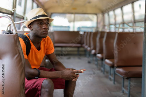 African tourist man thinking while holding mobile phone