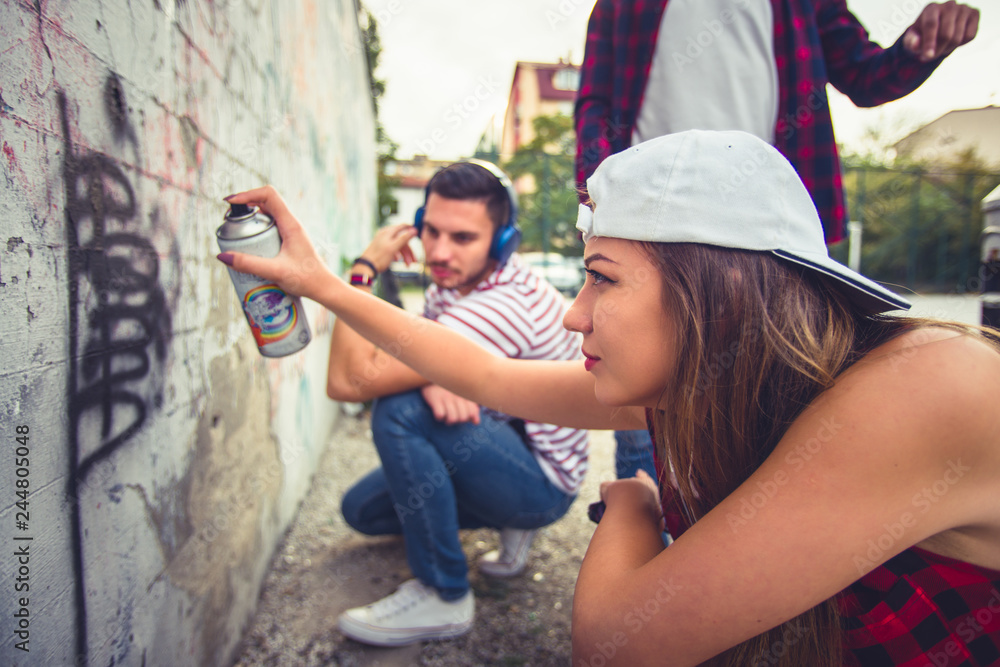 Naklejka premium Young careless people trying to do graffiti