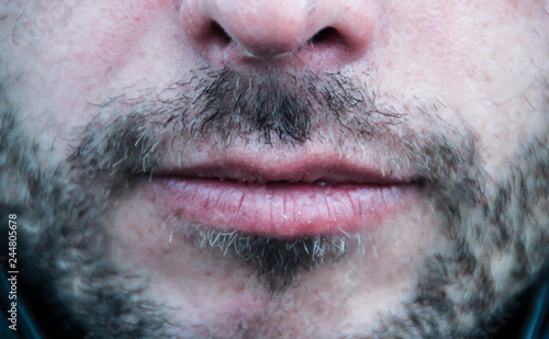 Beautiful thin men's lips and light unshaven face close up