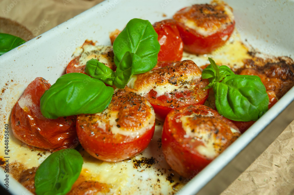 Closeup detail look on fresh vegetarian sliced and salted tomatoes ready to bake covered with cheese and fresh organic basil Closeup detail look on fresh vegetarian sliced and salted tomatoes ready to bake covered with cheese and fresh organic basil
