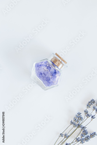 Flowers of lavender, decorative bottle with sea salts on the white background. Relaxing concept.