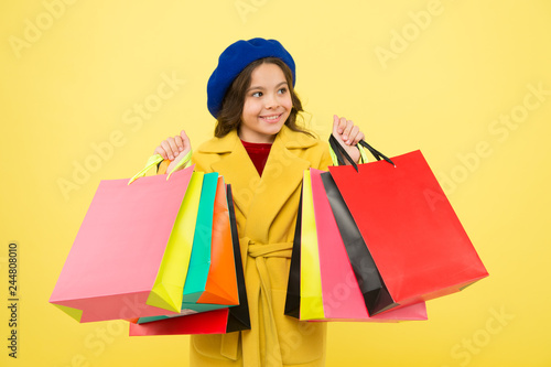 Get discount shopping on birthday or holiday. Fashionista adore shopping. Obsessed with shopping. Girl cute kid hold shopping bags on yellow background. Mid season sale. Shop with discount card