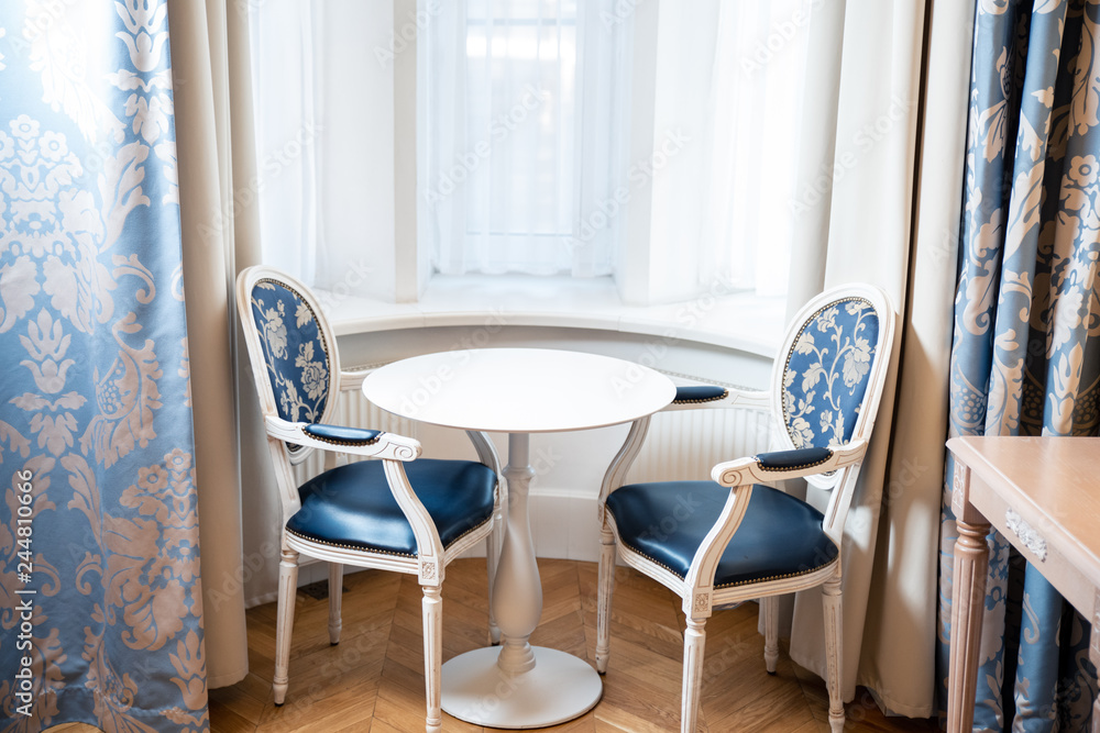 The interior of the room with a blue chair and a white table. The interior of the room with a blue chair and a white table.