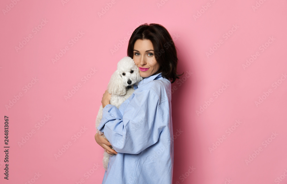 Beautiful woman hugging her lovely white poodle dog puppy on pink Beautiful woman hugging her lovely white poodle dog puppy on pink