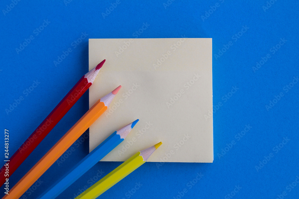 Top view of the empty blank for writing and color pencils on the blue background.Copy space. Top view of the empty blank for writing and color pencils on the blue background.Copy space.
