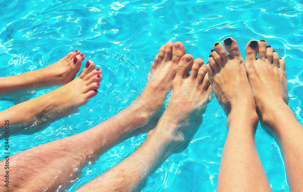 women's and men's feet in the pool. Vacation in summer in clear weather.