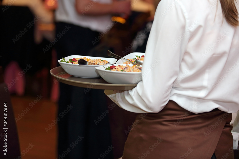 Kelnerka roznosi talerze z jedzeniem na sali w restauracji. - obrazy, fototapety, plakaty 