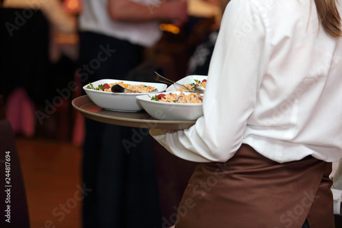 Kelnerka roznosi talerze z jedzeniem na sali w restauracji.