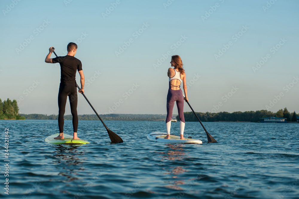 Athletic man and woman paddling on calm river