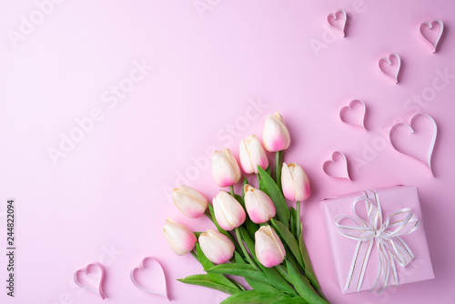 Valentines day and love concept. Pink tulips, gift box with heart on pink background.