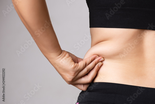 Fat woman hand holding excessive belly fat. Healthcare and woman diet lifestyle concept to reduce belly and shape up healthy stomach muscle. photo